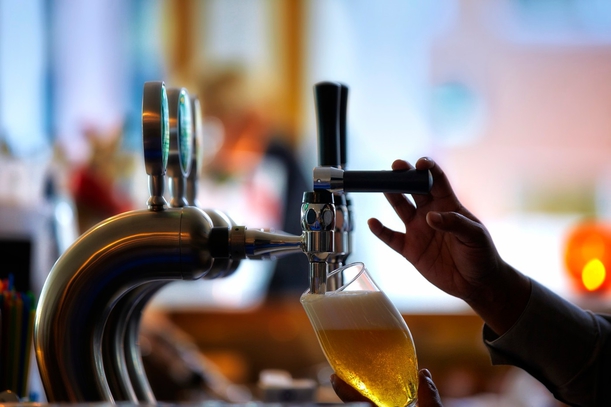 Close-up side view of glass of beer being poured from tap